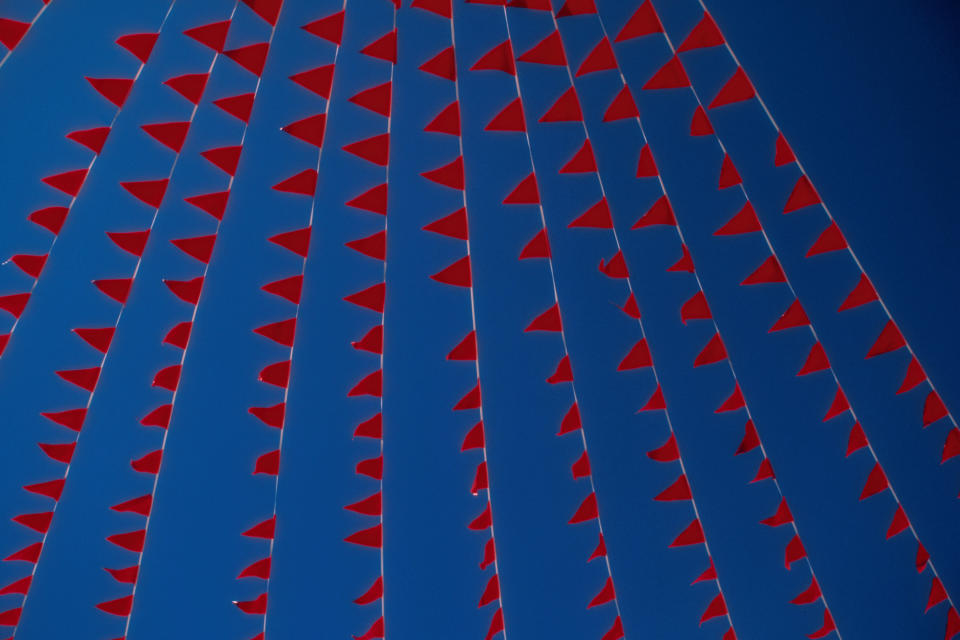 Bild von roten Fahnen vor blauem Himmel.